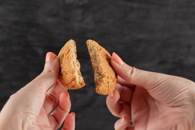 Een havermoutkoekje in de hand in twee stukken snijden.