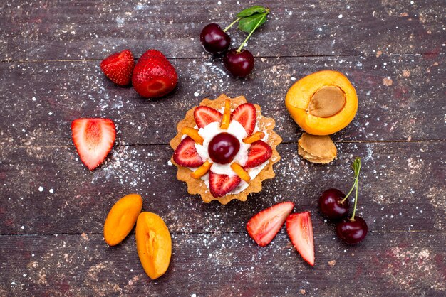 Een heerlijke kleine cake van bovenaf met room en vers gesneden fruit op het bruine koekje van de bureaifruit