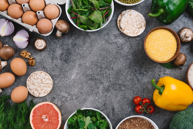 Een hoger beeld van groenten; walnoten; fruit en gepofte rijstwafel op grijze concrete achtergrond