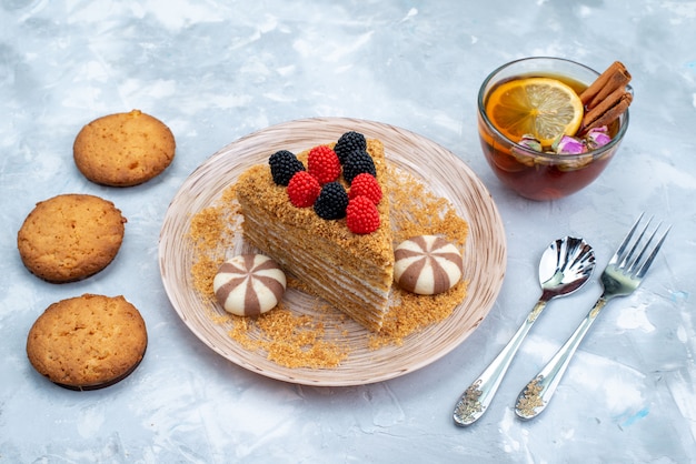 Een hoogste de cakeplak van de meningshoning binnen plaat met suikergoedkoekjes en thee op de blauwe cake van de achtergrondkoekjesthee