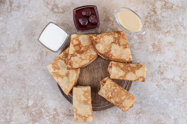 Een houten bord met lekkere pannenkoeken en aardbeienjam