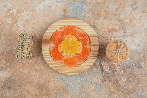 Een houten bord met marmelade en koekjes op marmeren achtergrond