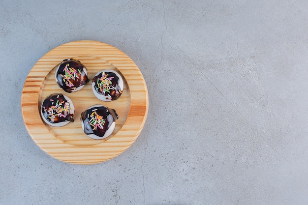 Een houten bord met smakelijke geglazuurde koekjes op stenen tafel.