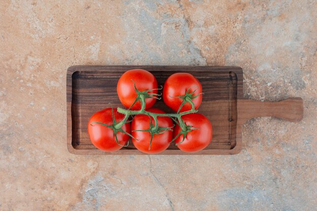 Een houten bord met verse tomaten op marmer