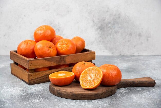 Een houten bord van sappige plakjes oranje fruit op stenen tafel.