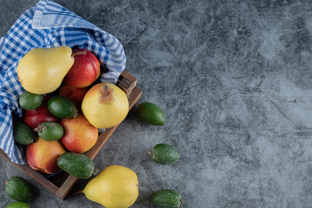 Een houten fruitschaal vol met peren, feijoa's en perziken