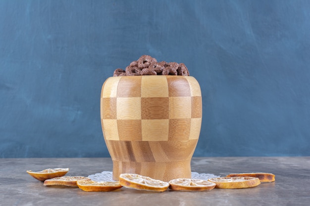 Een houten kom chocoladegranenringen met gesneden gedroogd sinaasappelfruit.