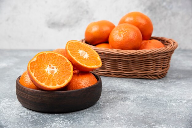 Een houten kom vol met sappig oranje fruit op stenen tafel.