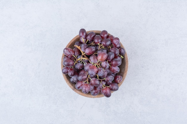 Een houten kom vol paarse druiven op witte achtergrond. Hoge kwaliteit foto