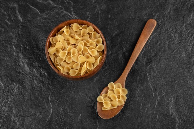 Een houten kom vol rauwe farfalle tonde macaroni.