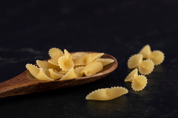 Een houten lepel vol rauwe farfalle tonde macaroni.