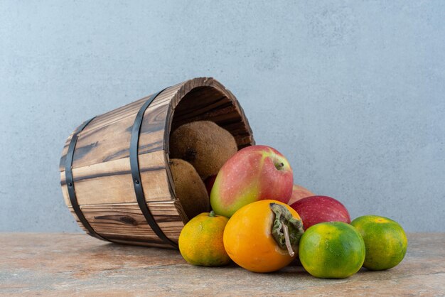 Een houten mandje met vers zoet fruit op grijs