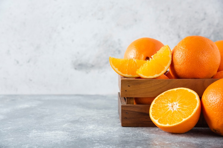 Gratis Foto een houten oude doos vol sappig oranje fruit op stenen tafel.
