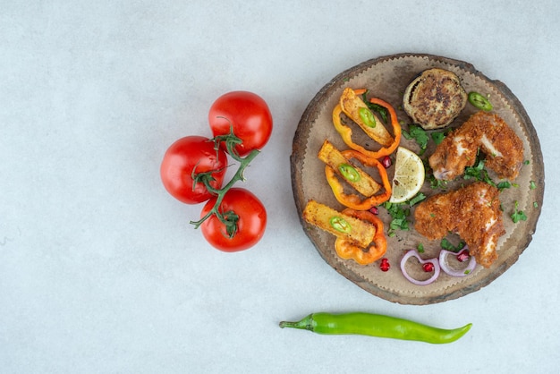 Een houten plaat met paprika's en tomaten op wit