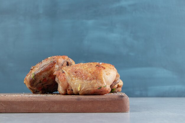 Een houten plank met gebakken kippenvlees met relish.
