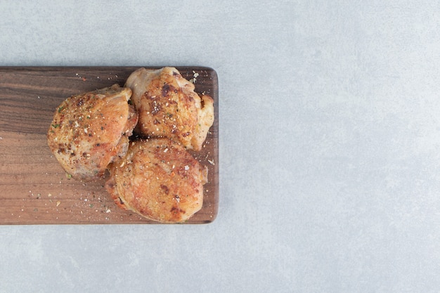 Een houten plank met gebakken kippenvlees met relish.
