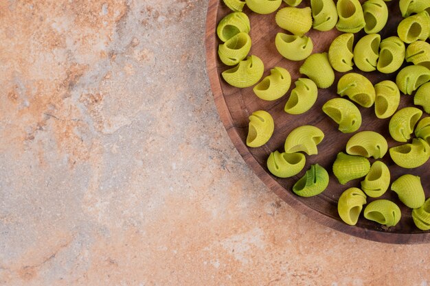 Een houten plank met groene onvoorbereide macaroni