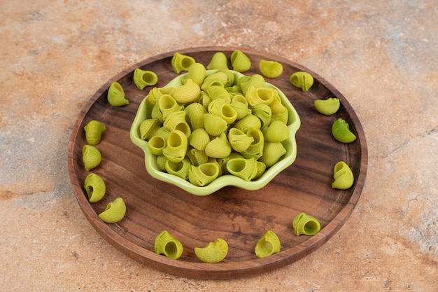 Een houten plank met groene onvoorbereide macaroni