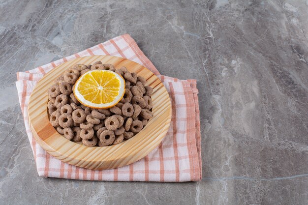 Een houten plank van gezonde chocoladegranenringen met een schijfje sinaasappelfruit.