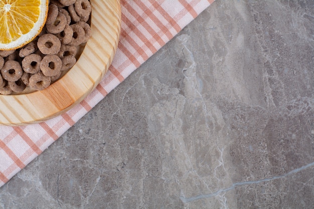 Een houten plank van gezonde chocoladegranenringen met een schijfje sinaasappelfruit.