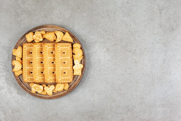 Een houten plank vol koekjes op marmeren achtergrond.