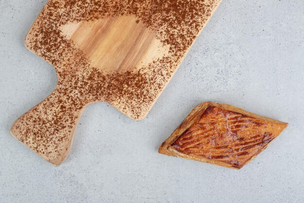 Een houten snijplank met cacaopoeder en koekje.