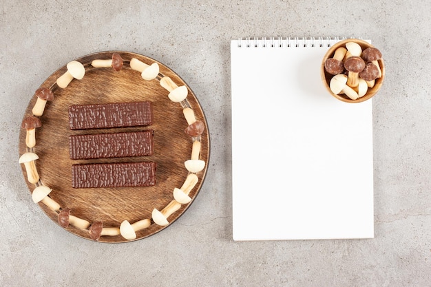 Een houten snijplank met drie chocolaatjes en een vel papier.
