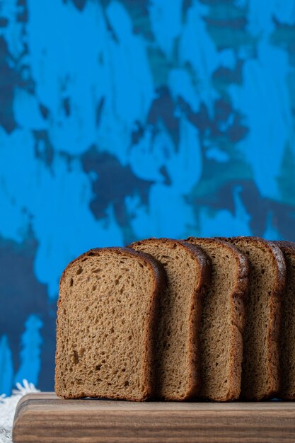 Een houten snijplank met sneetjes bruin brood.