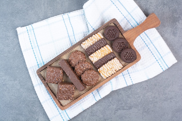 Een houten snijplank vol koekjes en chocolaatjes.