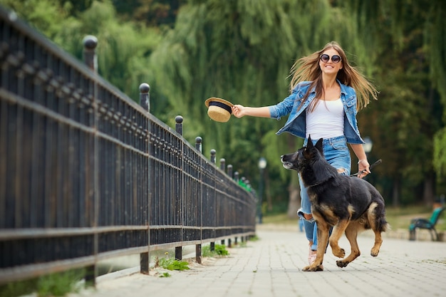 Een jong meisje loopt met een hond in het park
