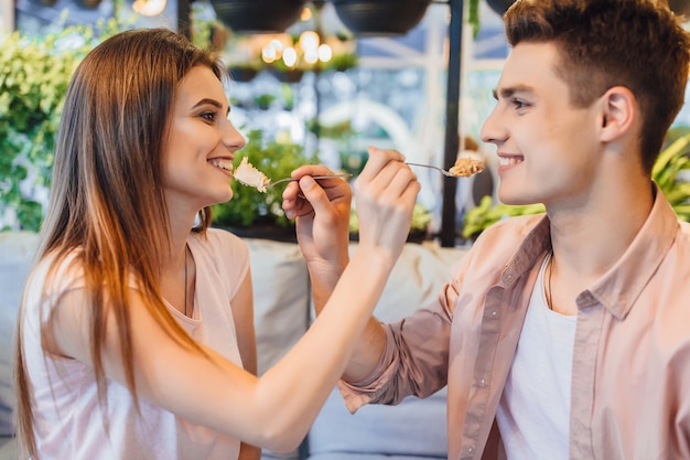 Een jong mooi stel voedt elkaar met een heerlijke taart. Liefhebbers in het café