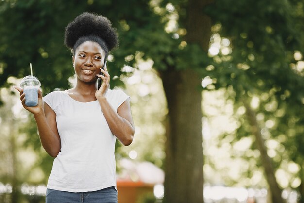 Een jonge Afro-Amerikaanse vrouw praat met een telefoon in het park