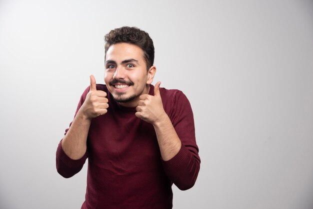 Een jonge brunette man duimen opdagen.