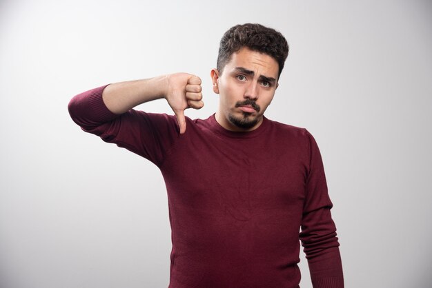Een jonge brunette man met een duim naar beneden.