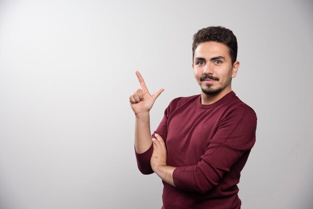 Een jonge brunette man met een vinger omhoog en poseren.