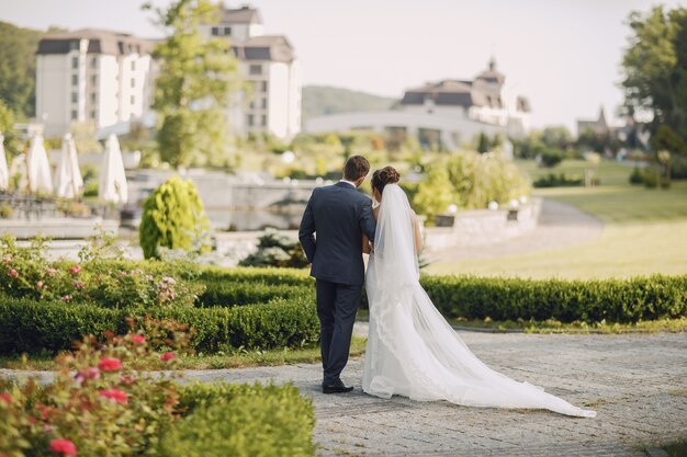 Een jonge en mooie bruid en haar echtgenoot die zich in park met boeket van bloemen bevinden