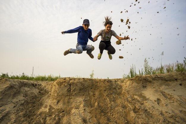 Een jonge kerel en een meisje springen van een hoge zandberg