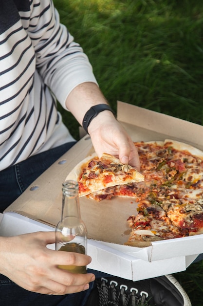 Een jonge man die pizza eet op een picknick