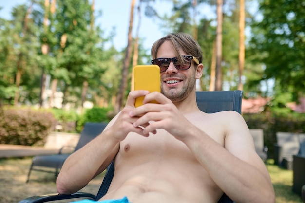 Een jonge man in zonnebril met een smartphone in handen