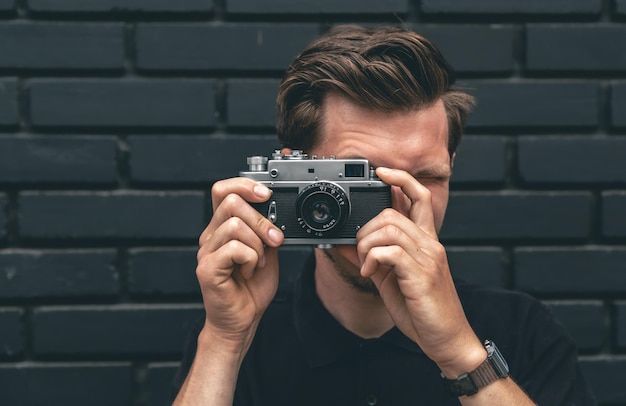 Een jonge man maakt een foto met een vintage filmcamera