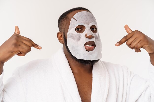 Een jonge man met een papieren masker op het gezicht die geschokt kijkt met een open mond geïsoleerd op een witte achtergrond