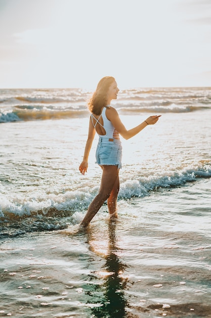 Een jonge mooie vrouw die overdag aan de kust loopt