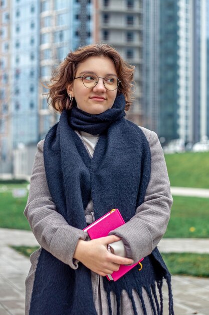 Een jonge student met een boek in haar handen gaat naar de universiteit.