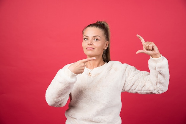 Een jonge vrouw die een sweater draagt die iets kleins met handen toont