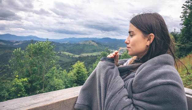 Gratis foto een jonge vrouw die koffie drinkt met uitzicht op de bergen