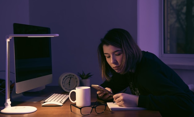 Een jonge vrouw die 's nachts op de werkplek werkt