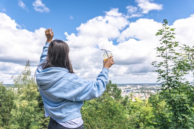 Een jonge vrouw die sap drinkt van een rietje in het park