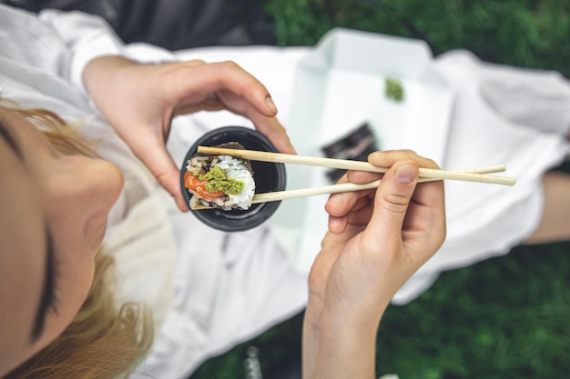 Gratis foto een jonge vrouw die sushi eet in de close-up van het makibroodje van de natuur