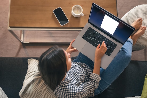 Een jonge vrouw die thuis op een laptop werkt