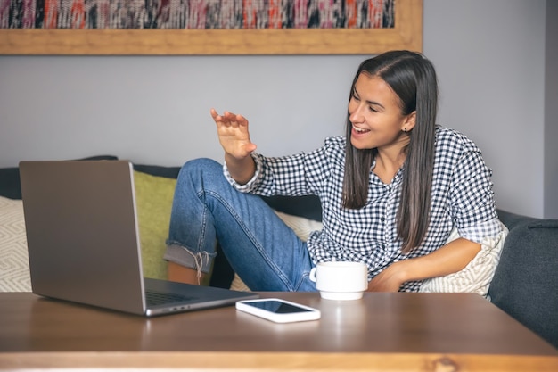 Een jonge vrouw die thuis op een laptop werkt